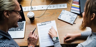 Two people reviewing a contract together, discussing client relationships and project details.