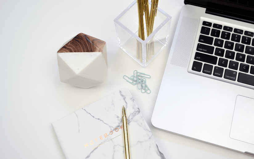 Freelancing concept: Laptop, notebook, pen, and desk accessories on a white workspace.