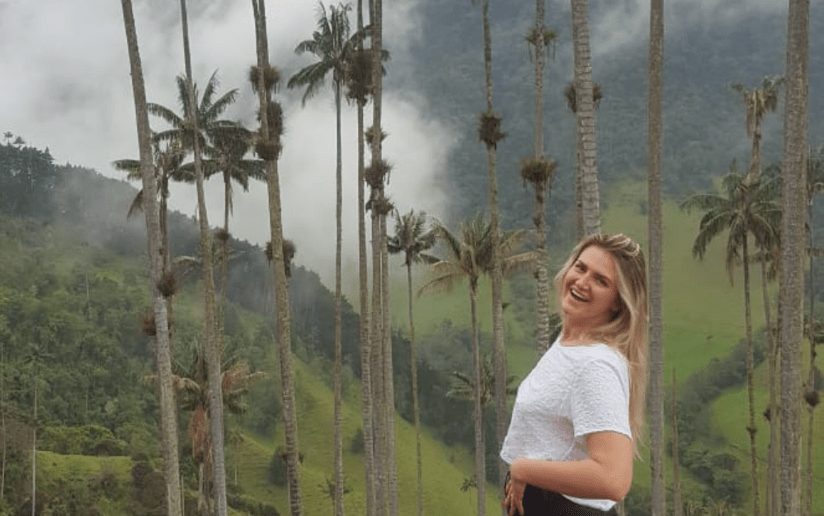 Amelia Clay smiling among tall wax palm trees in Cocora Valley, Colombia.