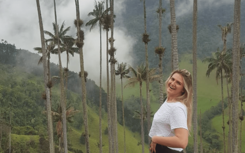 Amelia Clay smiling among tall wax palm trees in Cocora Valley, Colombia.