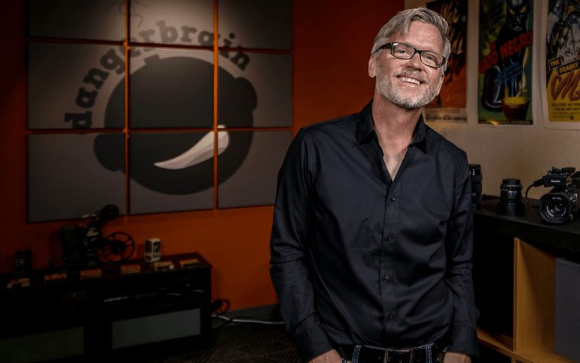 Bud Anderson of DangerBrain, a voice and video professional, smiles in his office.