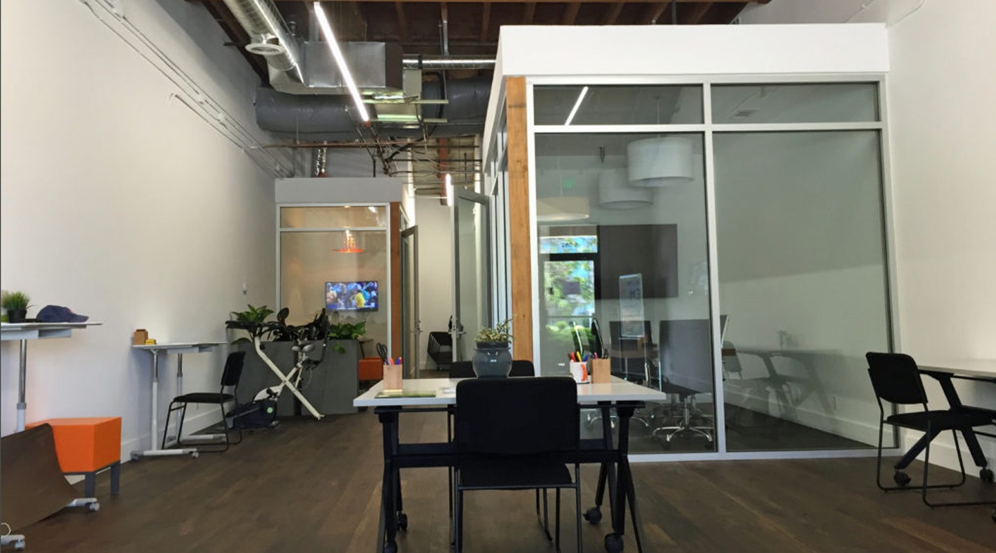 Modern office interior with glass-walled meeting rooms and open workspace.