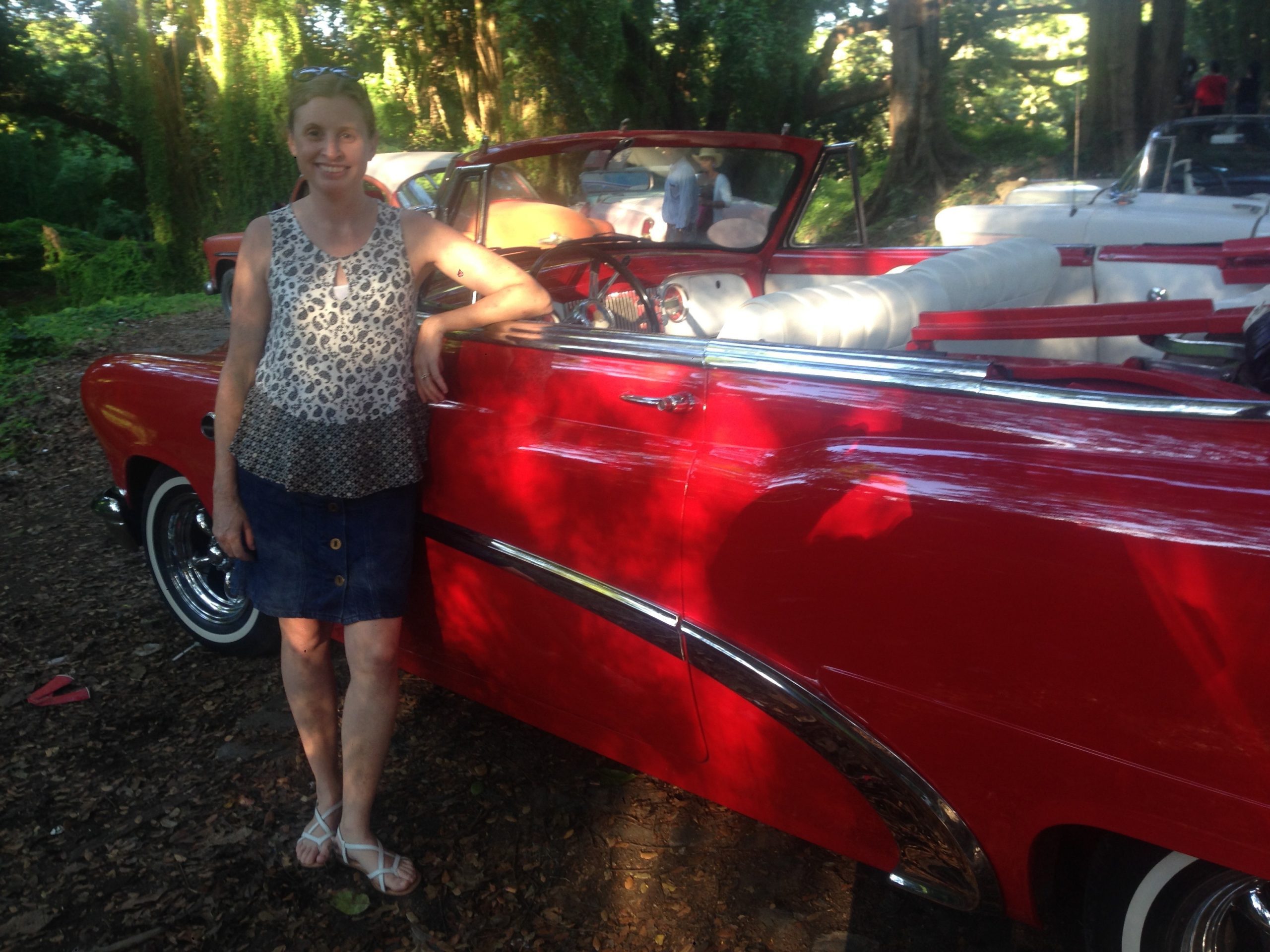 Colleen McCarthy with a classic red convertible, promoting community service and client dedication.