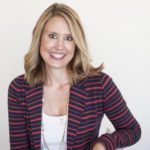 Woman smiling, wearing a striped blazer and white top