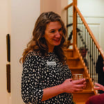 Woman at a networking event, smiling and holding a drink, making business connections.