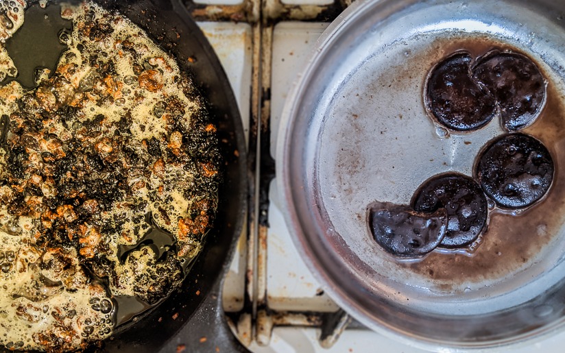 Burnt food in two pans on a stovetop, one cast iron and one stainless steel.