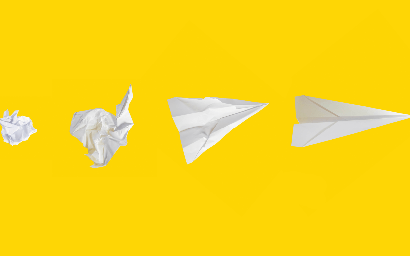 Paper airplane evolution: crumpled paper, unfolded paper, and finished paper airplane.