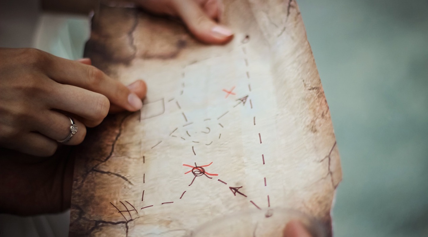 Hands holding a treasure map with an X marking a location; relevant to content mapping.