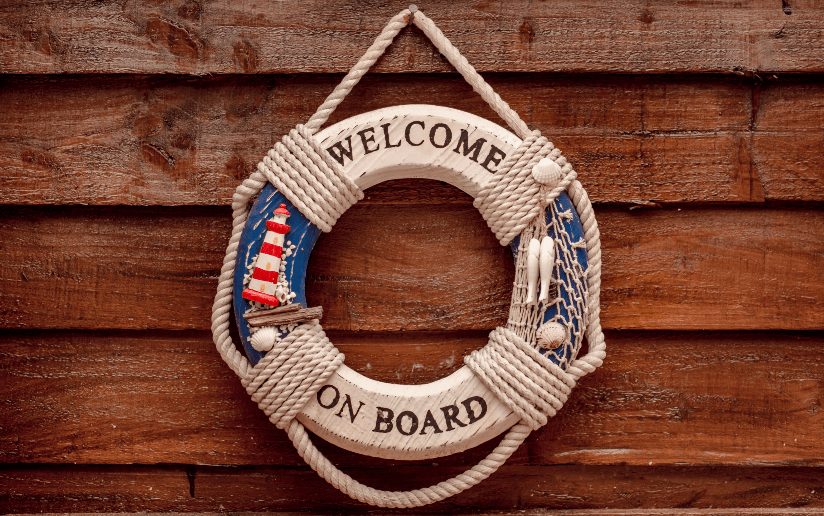 Nautical "Welcome On Board" life preserver decoration on a wooden wall.