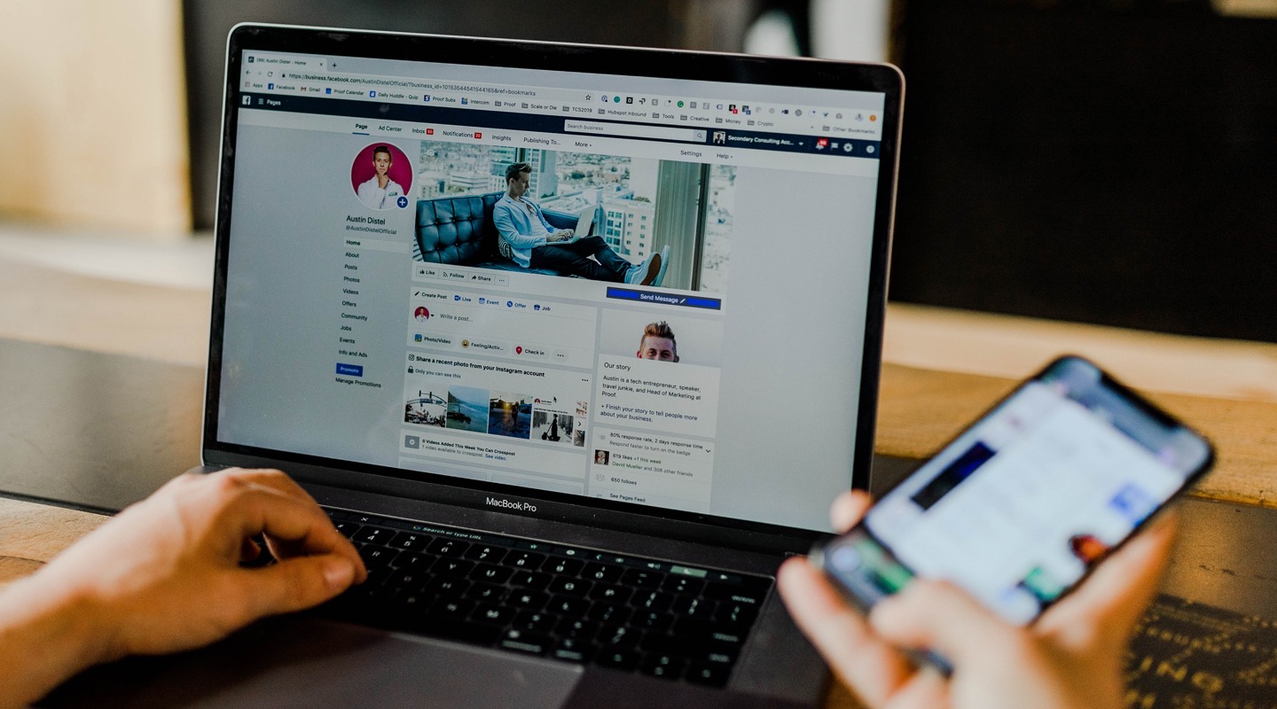 Person using MacBook Pro and iPhone, likely managing social media. Proof Marketing.