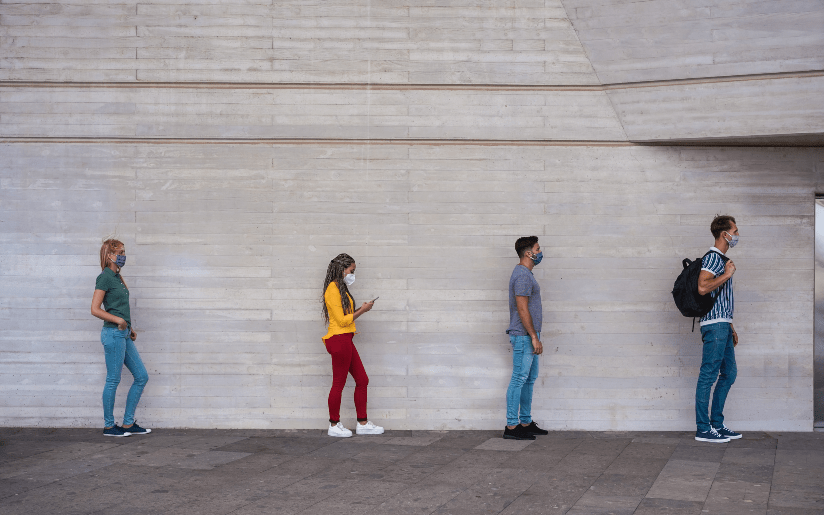 People socially distancing in line, wearing masks during the pandemic.