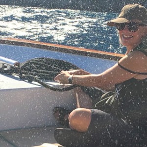 Woman steering a boat, enjoying a sunny boat trip on the ocean