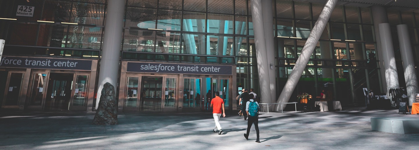 Salesforce Transit Center entrance with people walking by, modern architecture.