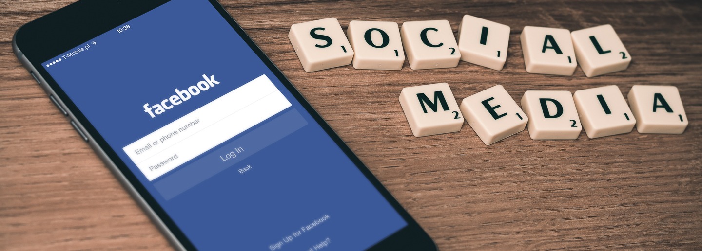 Facebook login screen on a smartphone with SOCIAL MEDIA spelled in tiles. Social media marketing.