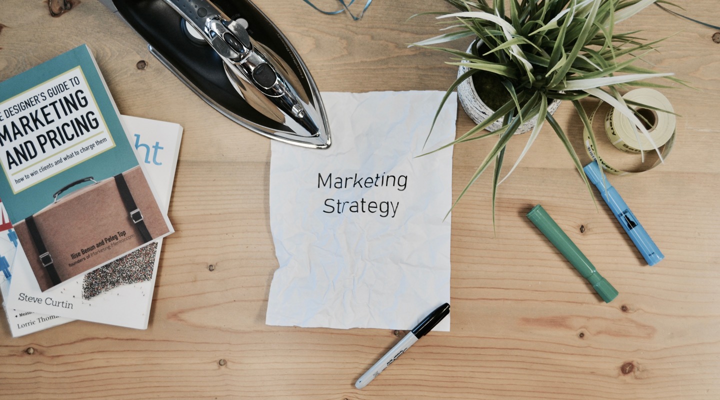 Marketing Strategy concept with books, iron, and markers on a wooden desk.