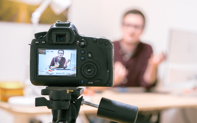 DSLR camera recording a video of a person explaining something for sustainable video content production.