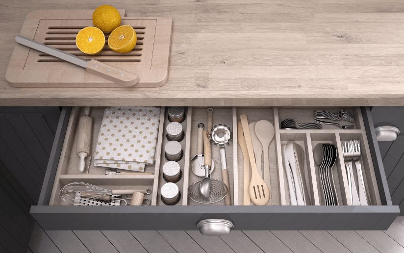Organized kitchen drawer with cooking utensils, rolling pin, cutlery, and wooden spoons.