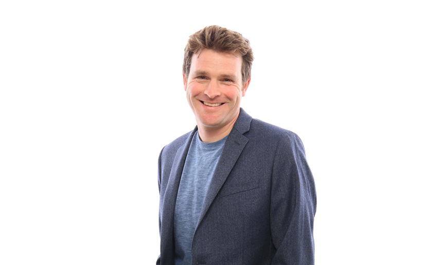 Smiling man in a blue blazer and t-shirt, looking at the camera