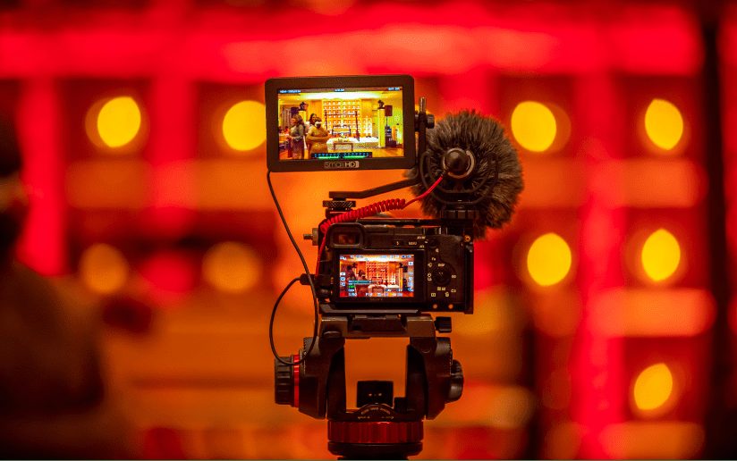 Camera with external monitor and microphone, filming a video project.