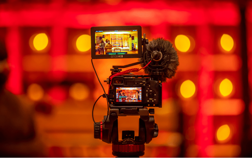 Camera with external monitor and microphone, filming a video project.