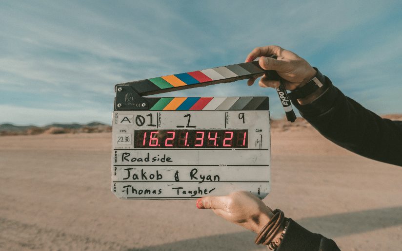 Film slate in desert setting for video project. "Roadside," "Jakob & Ryan" visible.