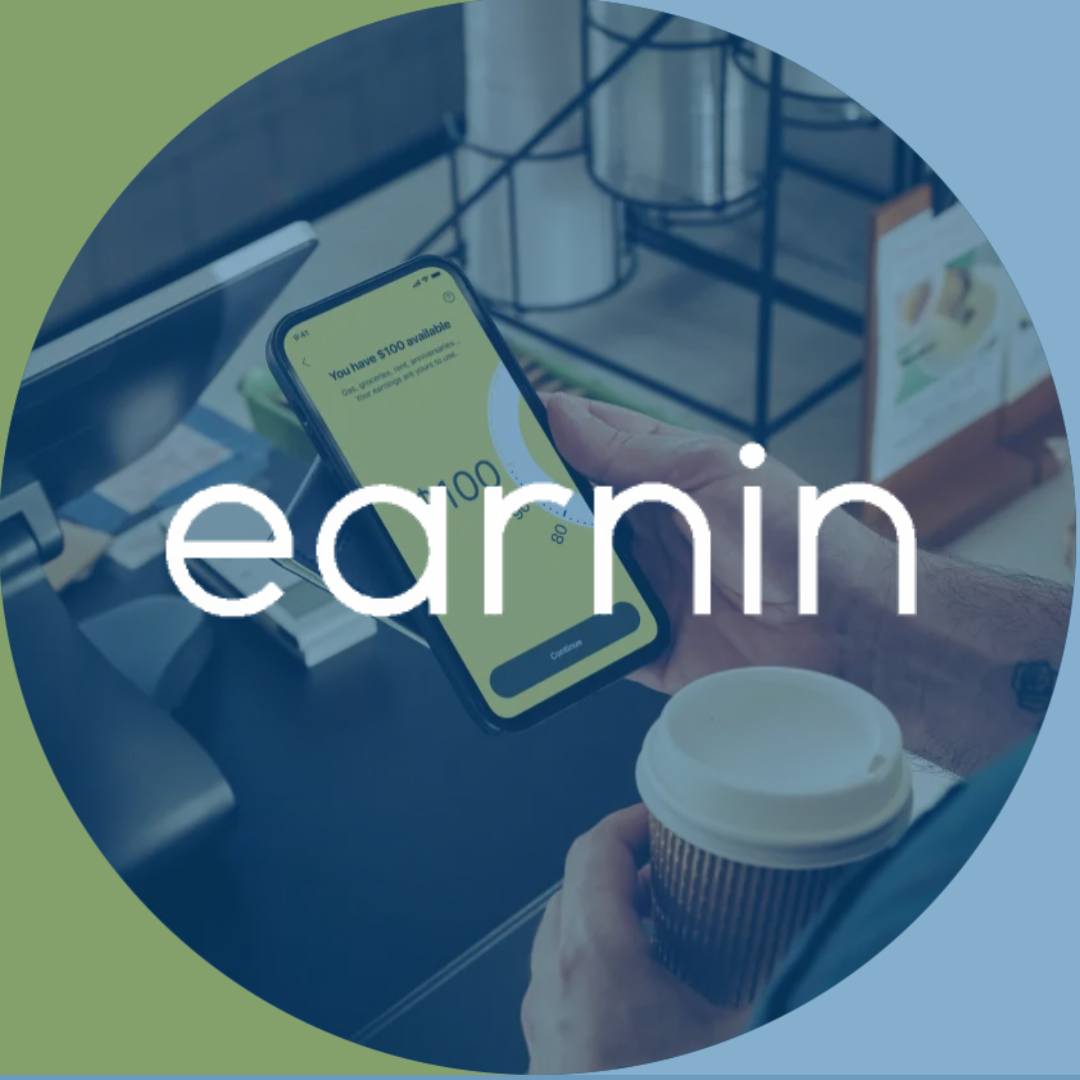 Person using the Earnin app on their phone, showing $100 available. Holding a coffee cup at a checkout.