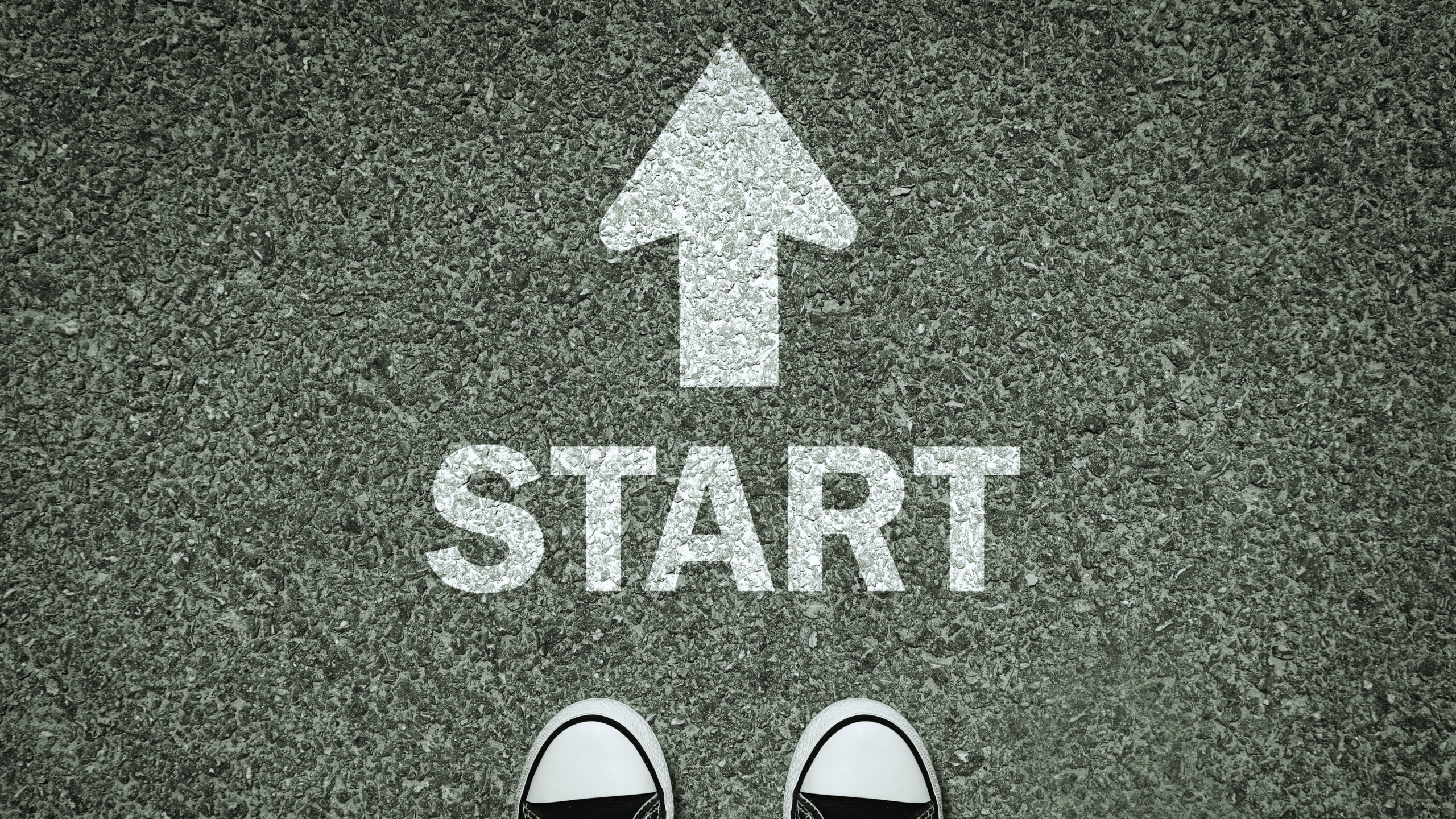 Sneakers facing START on asphalt, symbolizing new beginnings for 2025