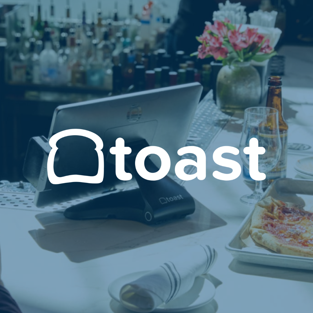 Toast POS system in a restaurant setting with pizza and beer on the bar